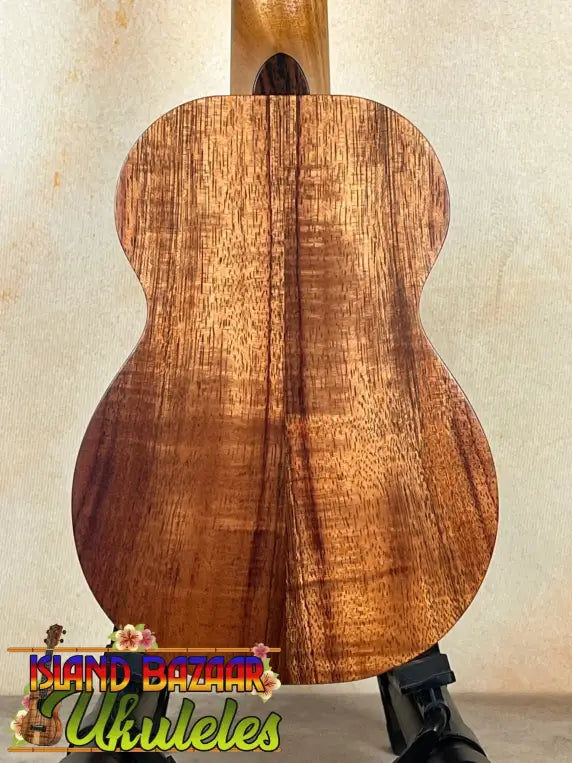 Wooden acoustic guitar with rich koa grain showcased with Kamaka Soprano Ukulele HF-1