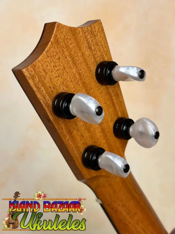 Guitar headstock with silver tuning pegs on a wooden surface of Kamaka Soprano Ukulele HF-1