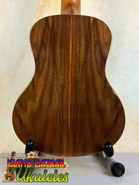 Wooden acoustic guitar with dark grain on stand, featuring Flight Sophia Soundwave Tenor