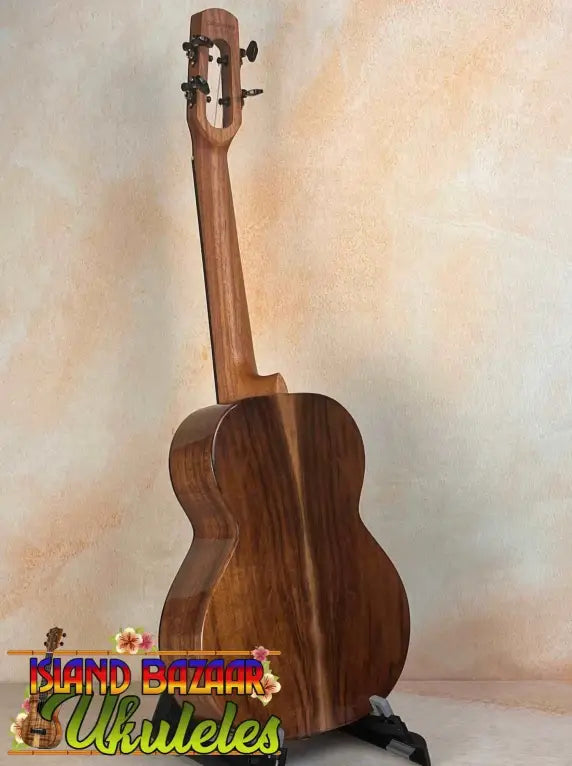 Wooden ukulele with rich brown finish on stand, part of Flight Voyager Tenor series
