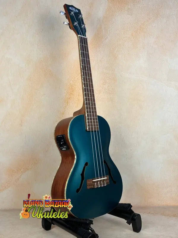 Teal Kala Archtop Tenor Ukulele KA-JTE-BKGN on a black stand, classic archtop design