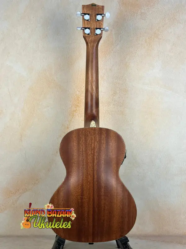 Wooden acoustic guitar with dark brown finish on black stand, Kala Archtop Tenor Ukulele