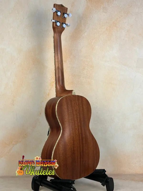 Wooden Kala Archtop Tenor Ukulele KA-JTE-BKGN on a black stand showcasing classic design