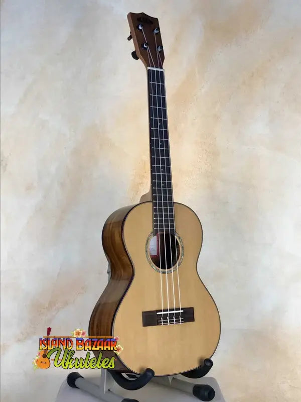 Natural wood Acacia Tenor Ukulele on a black stand, perfect for Island Bazaar Ukes