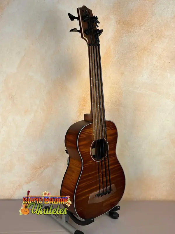 Wooden Kala Left-Handed U-Bass Ukulele in Exotic Mahogany resting on a stand