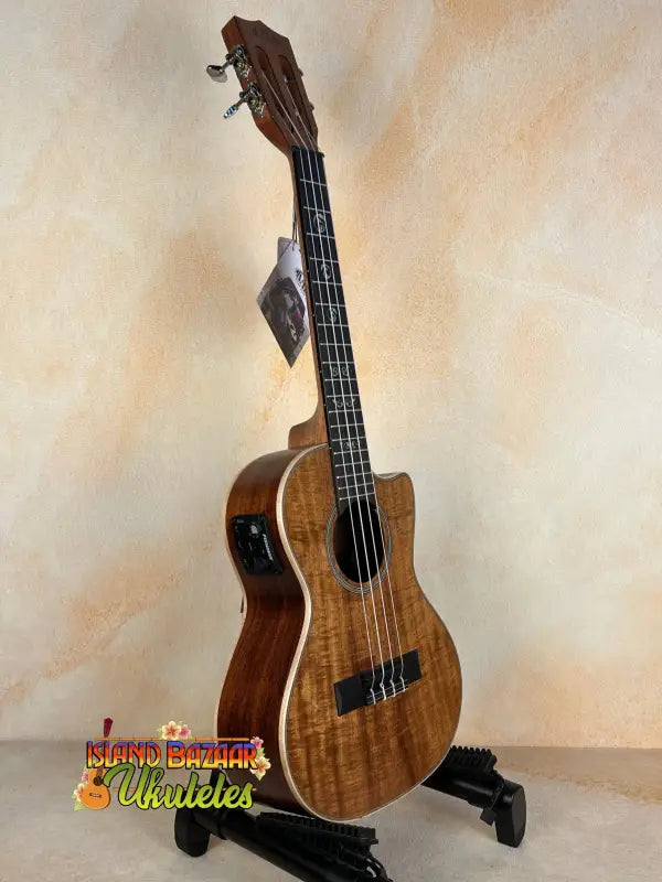 Wooden ukulele with a glossy finish on a stand, featuring the Kala SA-TE-C Tenor Electric