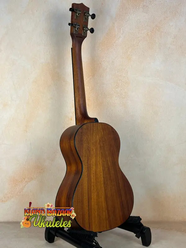 Wooden Kala Satin Hawaiian Koa Tenor Electric Ukulele on a black stand