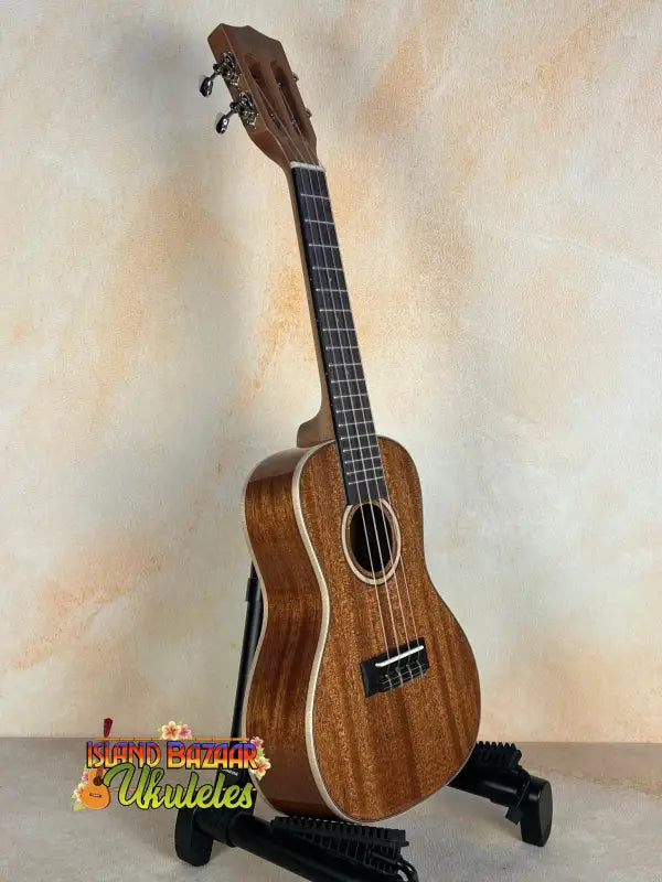 Wooden Kala SMH-CG Concert Ukulele on a black stand showcasing solid mahogany elegance