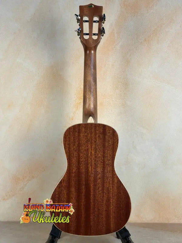 Wooden acoustic guitar with mahogany body on stand, showcasing Kala SMH-CG Concert Ukulele