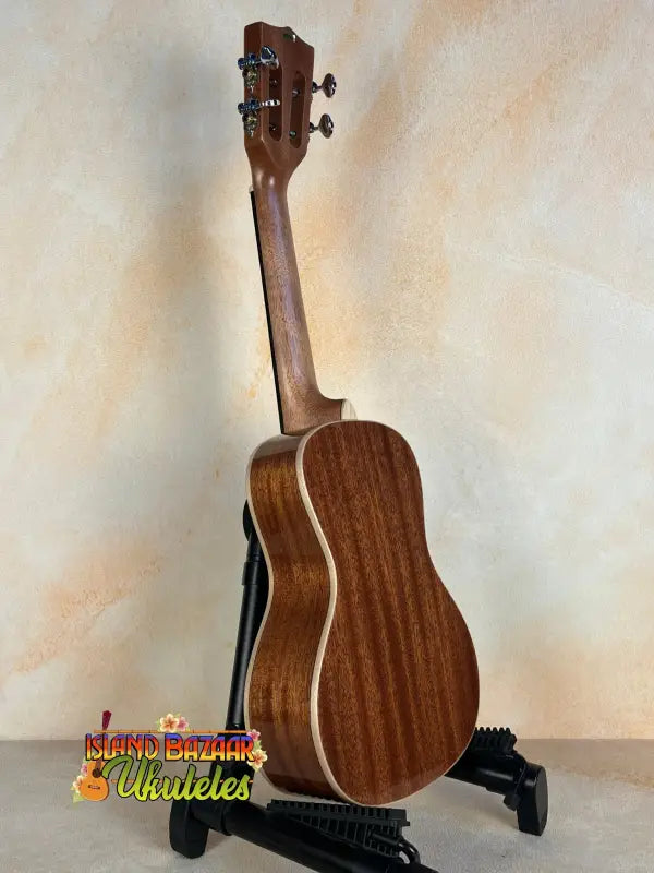 Wooden Kala SMH-CG Concert Ukulele on a black stand showcasing solid mahogany design