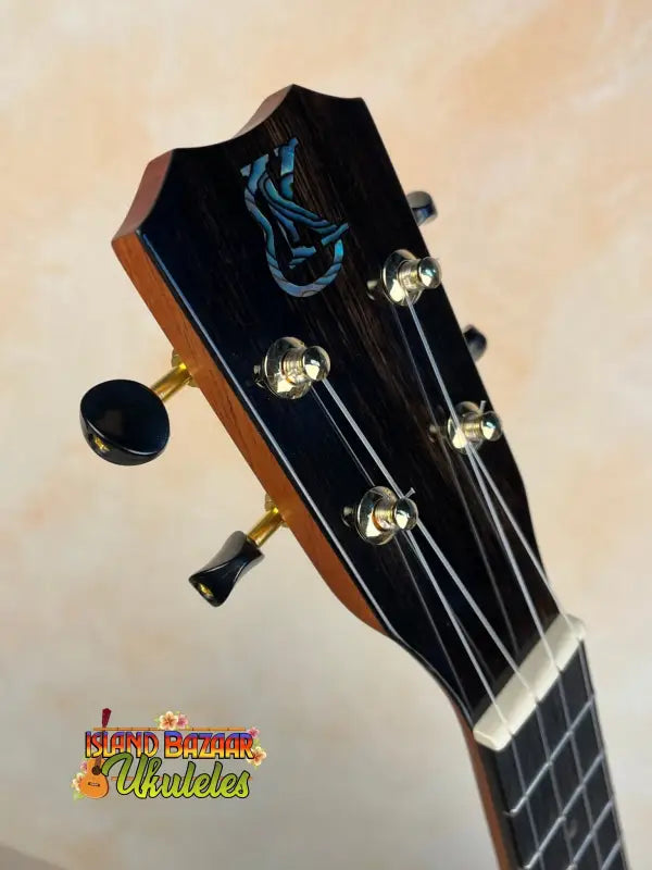 Guitar headstock with blue phoenix inlay and chrome tuning pegs on Kanile’a Concert Ukulele