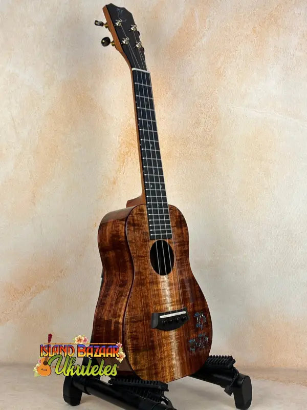 Beautiful Koa wood Kanile’a Concert Ukulele on a black stand with Deluxe Gig Bag