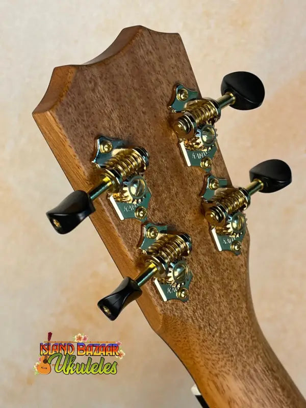 Guitar headstock with gold tuning pegs and black knobs on Kanile’a Hawaiian Islands Ukulele