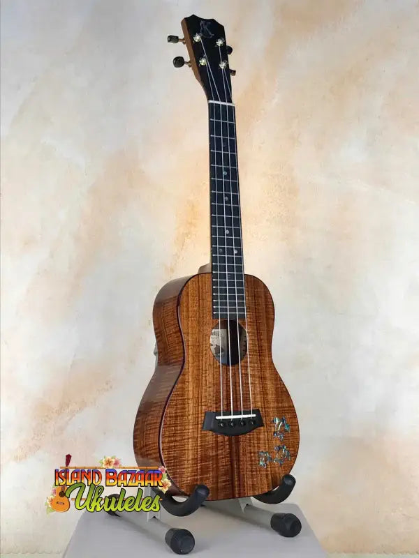 Beautiful Curly Koa Kanile’a HNS-T-PREM Concert Ukulele on display with padded gig bag
