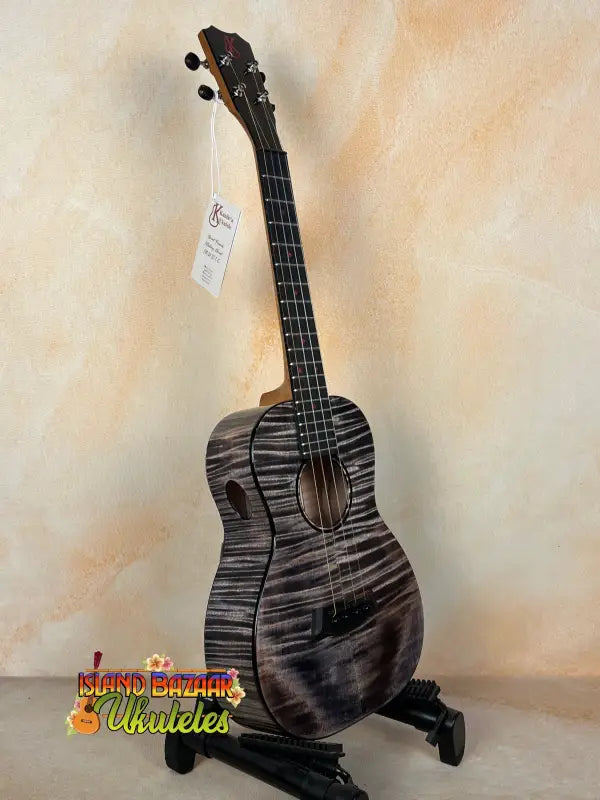 Black and gray Kanile’a KPA Pro Tenor Ukulele on a stand with deluxe gig bag
