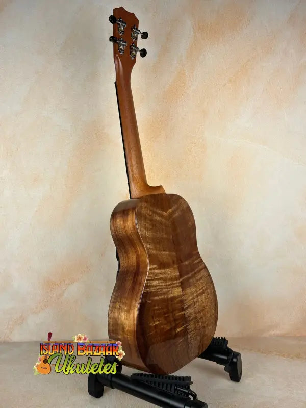 Brown wooden Kanile’a Tenor D-1 Ukulele on a stand with Deluxe Gig Bag