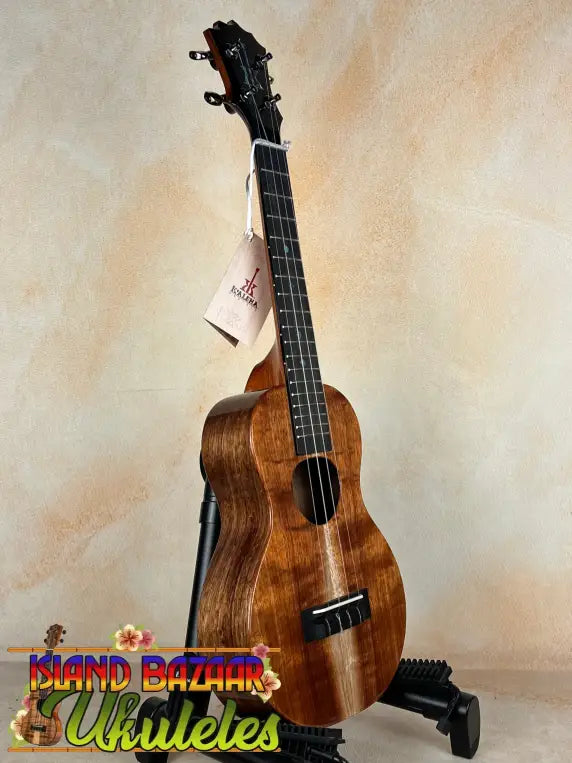 Wooden ukulele with dark grain on stand, showcasing KoAloha Concert Hawaiian craftsmanship