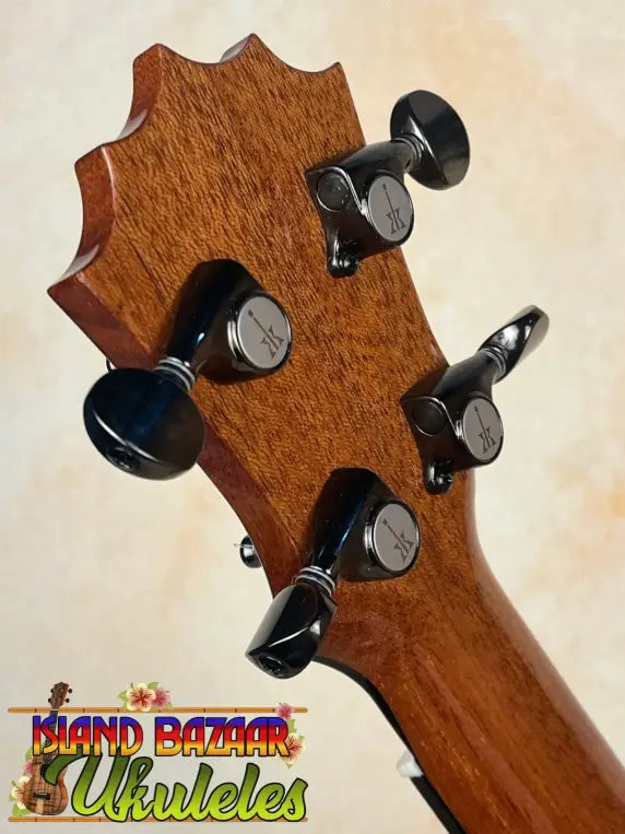 Guitar headstock with black tuning pegs and brown wood grain for KoAloha KSM-00 Soprano Ukulele