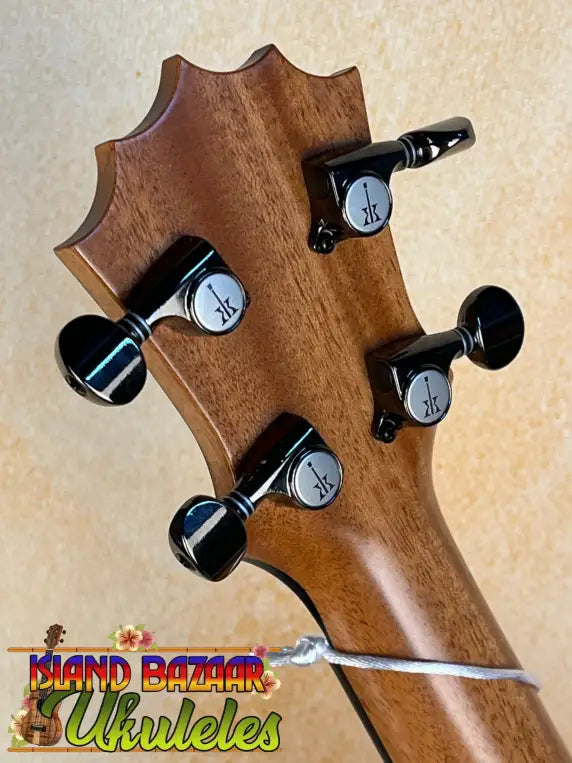 Guitar headstock of KoAloha Royal Pikake Concert KCM-00RP with black tuning pegs and broken string