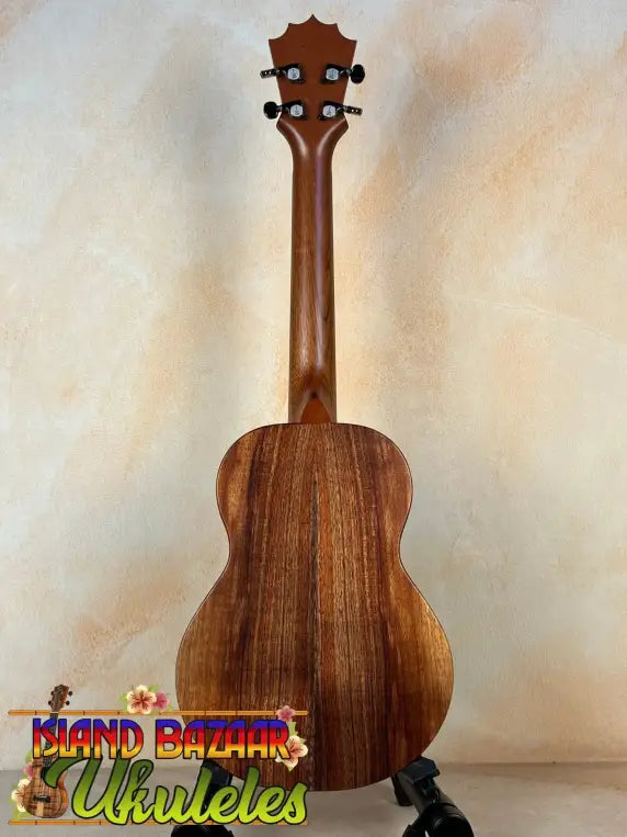 Wooden Koaloha Royal Pikake Tenor Ukulele with natural grain on a black display stand