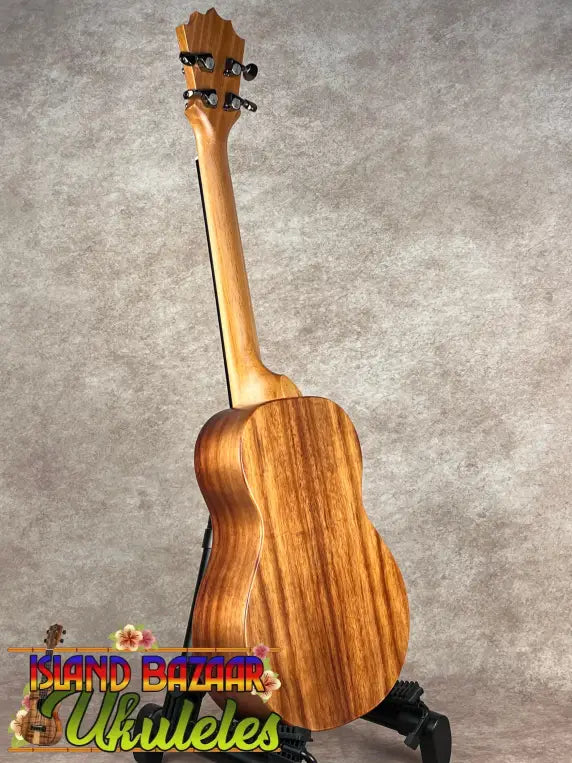 Light-colored wooden Koaloha Tenor ukulele with matte finish on dark stand showcasing Hawaiian ukulele craftsmanship