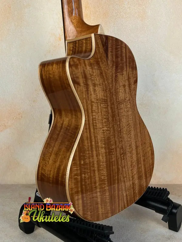 Acoustic guitar with walnut back on stand, featuring Luna Vista Deer Tenor Electric design