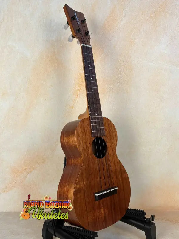 Wooden Kamaka Concert Ukulele HF-2 in solid koa on a black stand with hard case