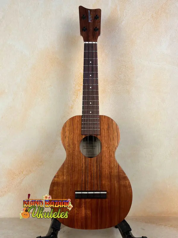 Wooden Kamaka Concert Ukulele HF-2 in Solid Koa on black stand with dark fretboard