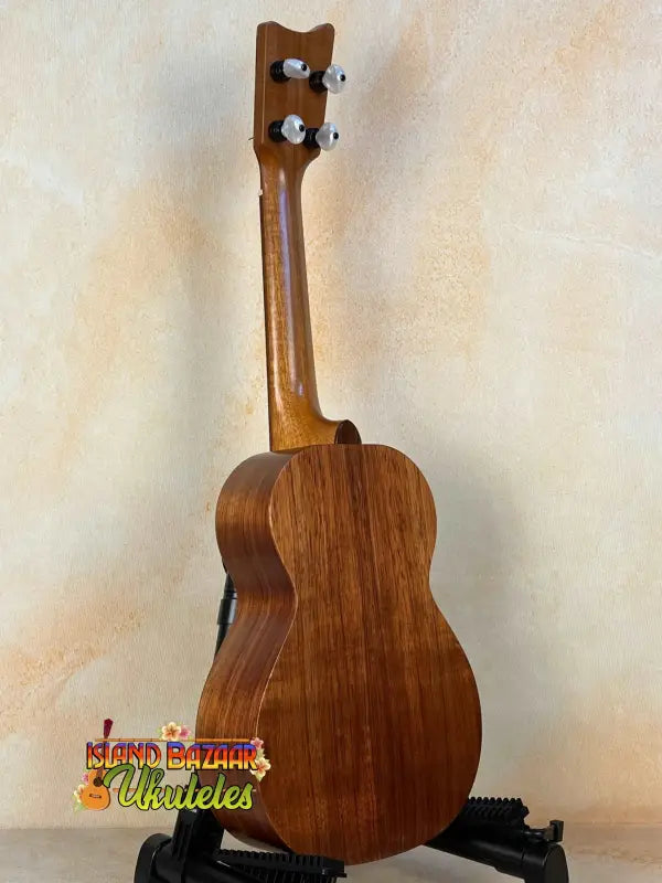 Wooden Kamaka Concert Ukulele HF-2 with tuning pegs on a stand and deluxe hard case