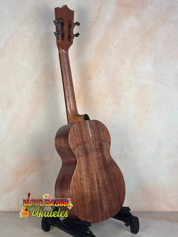 Wooden Kamaka HF-3I Slothead Tenor Ukulele on a black stand for display