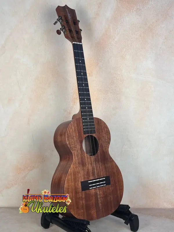 Wooden Kamaka HF-3I Slothead Tenor Ukulele on a black stand for display