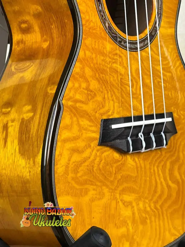 Golden-hued acoustic bass guitar showcasing quilted wood grain for Ohana CK-150SMP