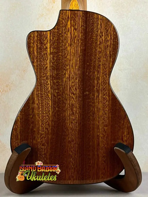 Acoustic guitar with wooden back on stand, showcasing Ohana CK-60CG Mahogany Concert Ukulele