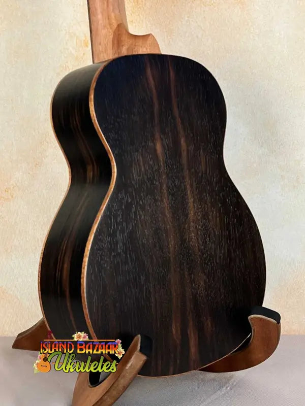 Dark wooden acoustic guitar features curved sides, highlighting Ohana TK-50ME Tenor Ukulele