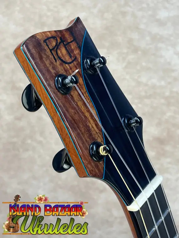 Polished Koa ukulele headstock with PCH logo, Malaysian blackwood accents