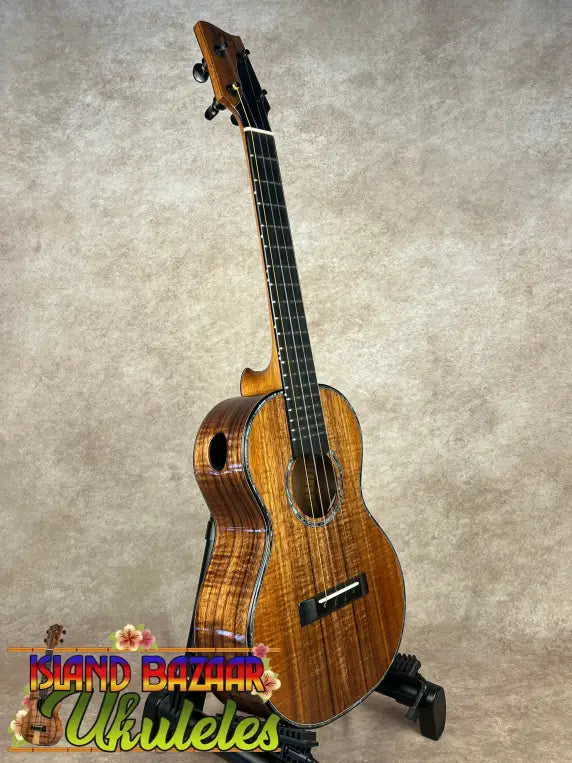Glossy solid Hawaiian Koa PCH Sunshine Tenor Ukulele with ebony fretboard on stand