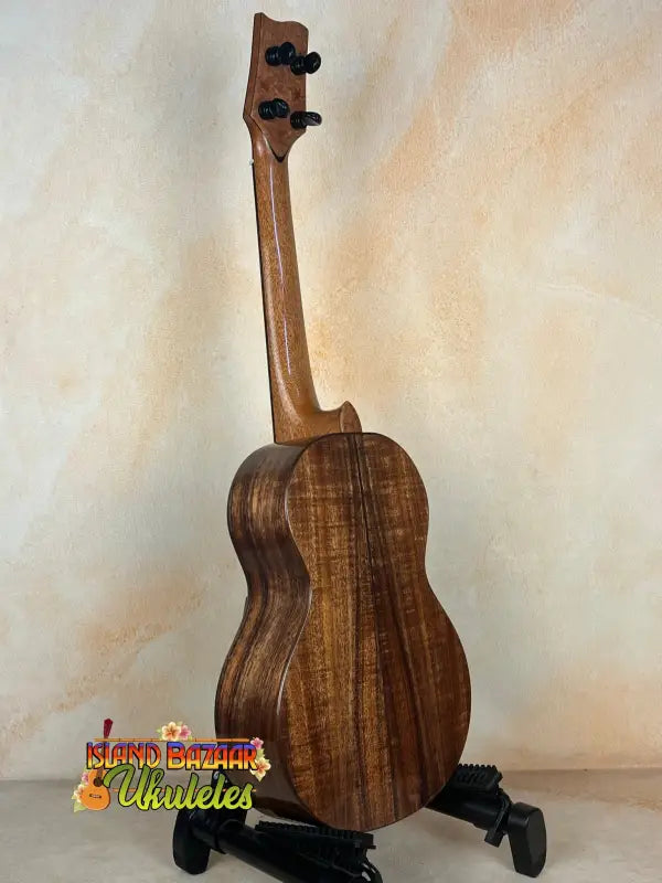 Wooden ukulele with rich brown grain on stand from Phil Henderson Ukuleles Chocolate Thunder Solid Koa Tenor