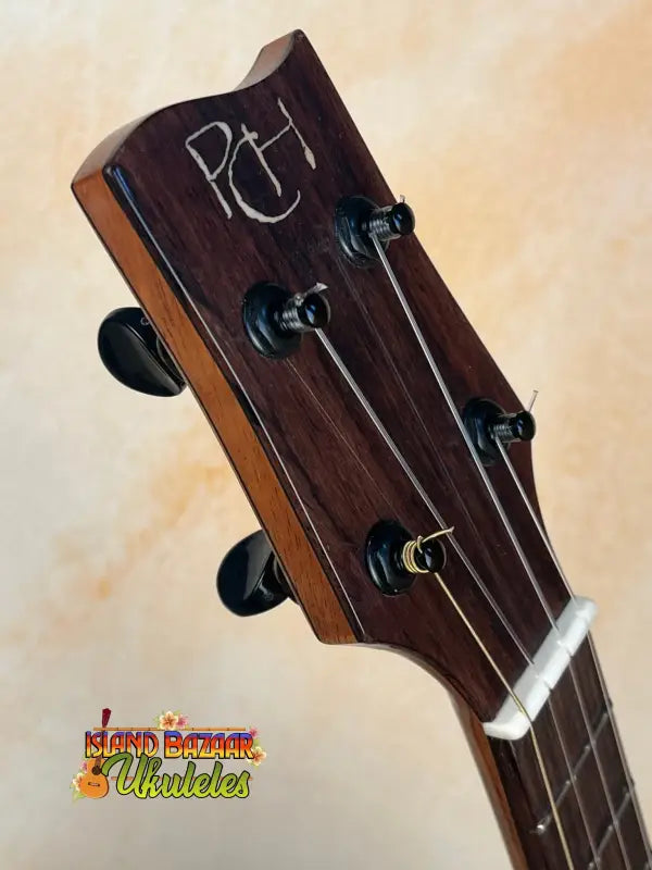 Dark wooden guitar headstock with black tuning pegs for Phil Henderson Ukuleles Chocolate Thunder Solid Koa Tenor