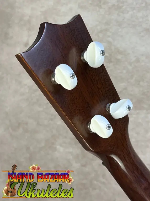 Dark brown wooden vintage martin custom baritone ukulele headstock with four white plastic tuning pegs
