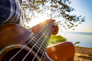 Ukulele player on the beach at sunset – tropical vibes and acoustic inspiration with Island Bazaar Ukes