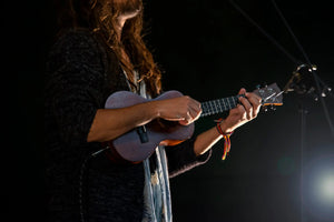 ukulele player strumming at sunset with glowing horizon – play ukulele anywhere for joyful moments
