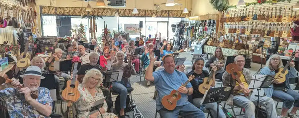 Inside Island Bazaar Ukes in Huntington Beach – many people playing ukuleles at an group ukulele jam