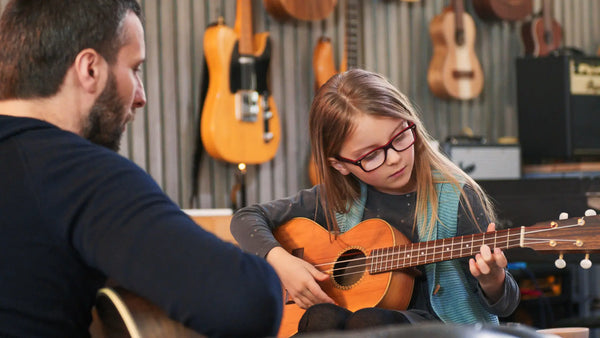 Young girl learning ukulele with instructor at Island Bazaar Ukes music lesson studio – beginner ukulele class for kids