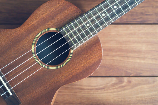 close-up of a mahogany soprano ukulele on wood background – best ukulele for beginners with warm tone