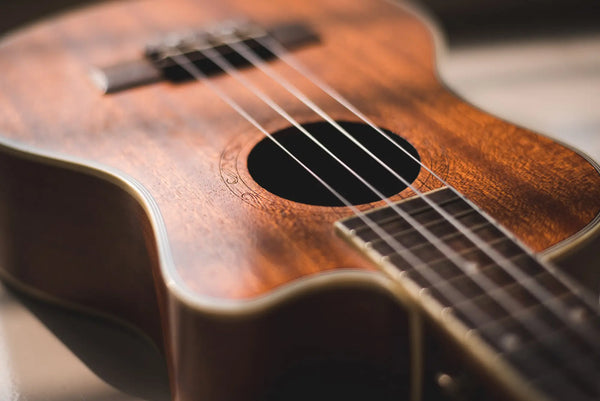 close-up of koa wood ukulele bridge and strings – Hawaiian koa ukulele craftsmanship