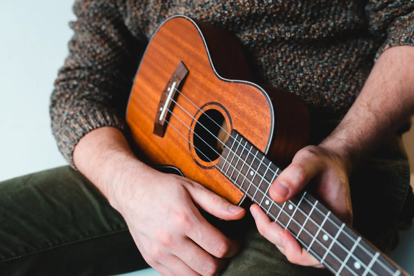 Close-up of adult playing a natural wood soprano ukulele – premium ukulele accessories and instruments at Island Bazaar Ukes