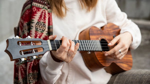 Woman playing high-end slotted headstock ukulele – exotic wood ukuleles available at Island Bazaar Ukes