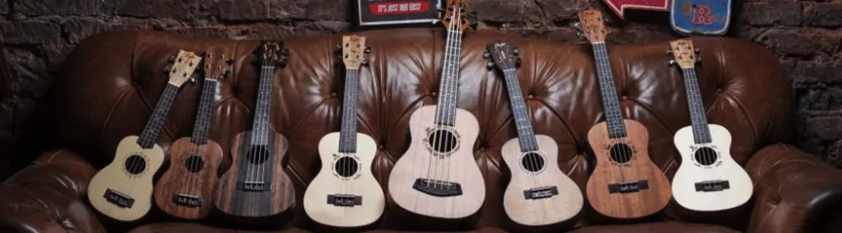 Colorful Flight Ukuleles including tenor electric ukulele lined on a leather couch.