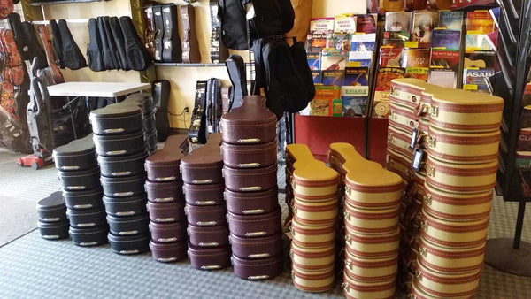 Stacks of hockey pucks in columns beside Kala Archtop baritone ukulele case.