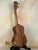 Wooden Concert Acacia Ukulele showcasing wood grain on a stand in a beginners bundle